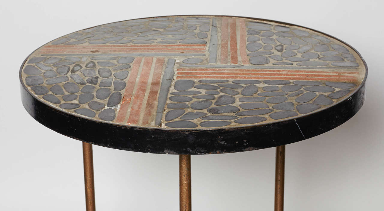Table has painted iron base with stones and terracotta tile top set in cement with iron outer edge.